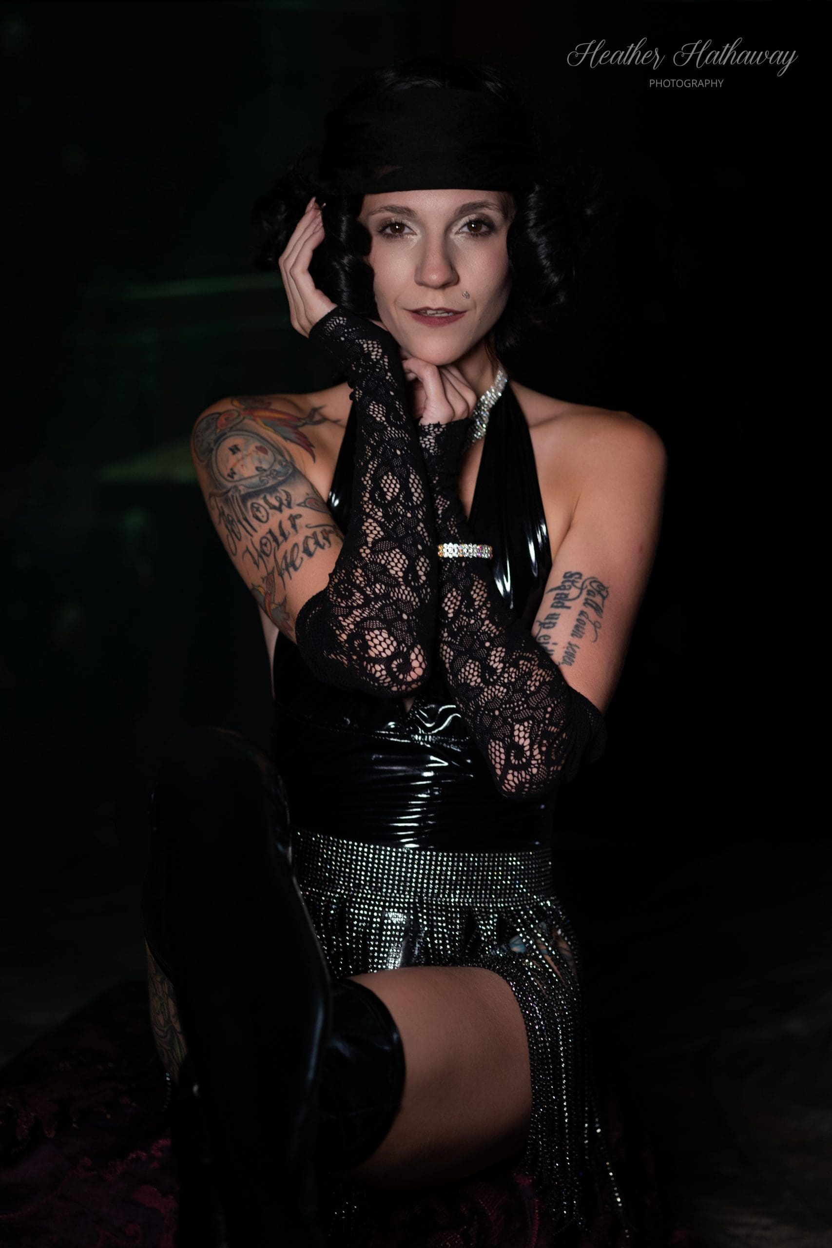 Boudoir portrait of a woman with black hair and tattoos in a fringe-styled setting, photographed in a tasteful empowerment session.