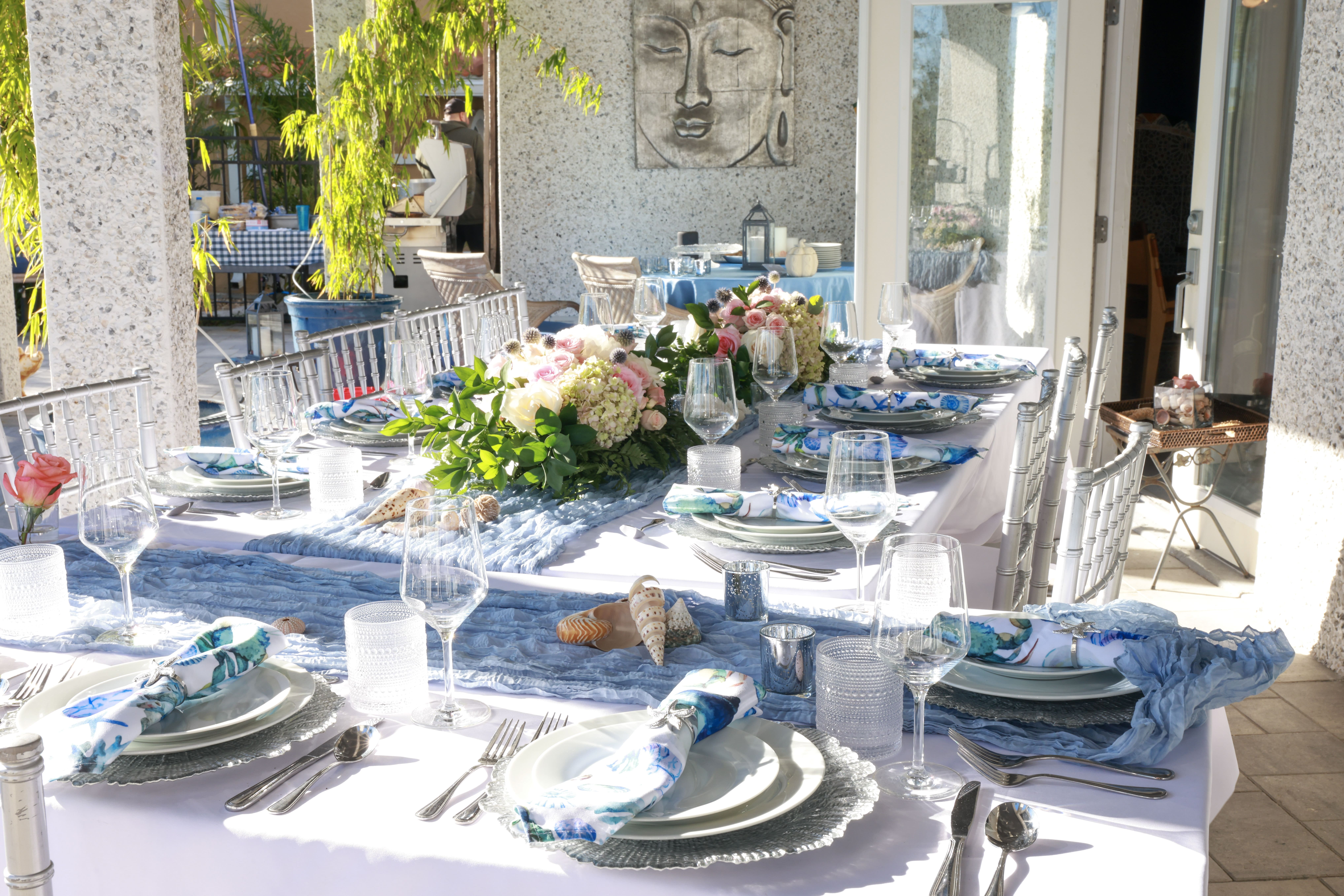 The flowers are center and blue and white plate settings surround a white draped table.