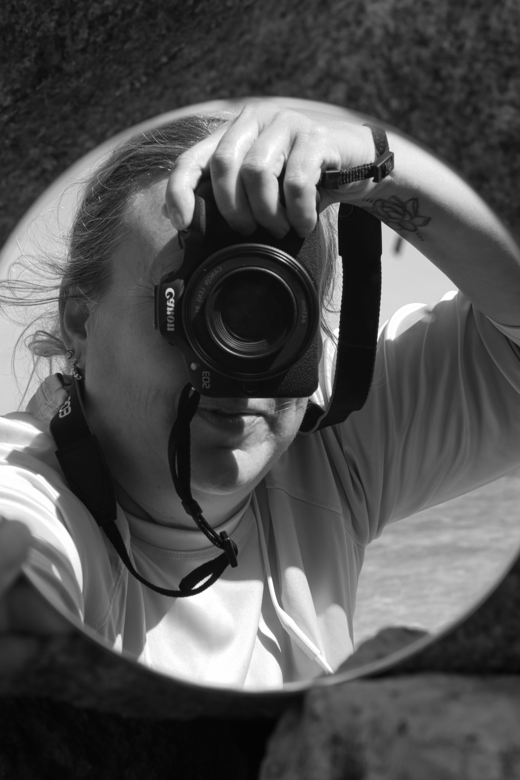 A self portrait (reflection) of photographer Heather Hathaway behind her Canon Camera.