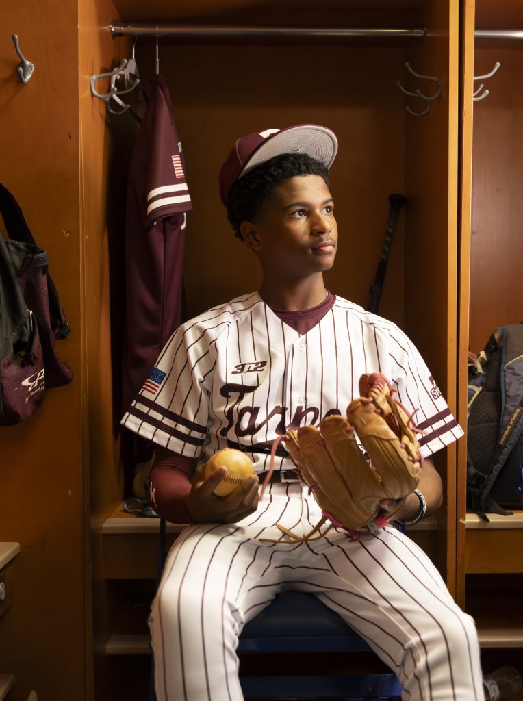 Tarpon Springs High School baseball player sitting in the locker room before a game, senior sports portrait in Tarpon Springs, Florida.